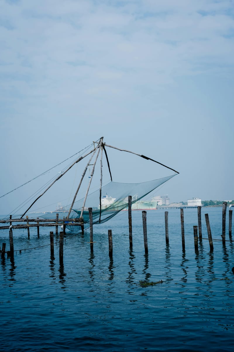 Iconic Chinese fishing net silhouette over calm water, port haze beyond